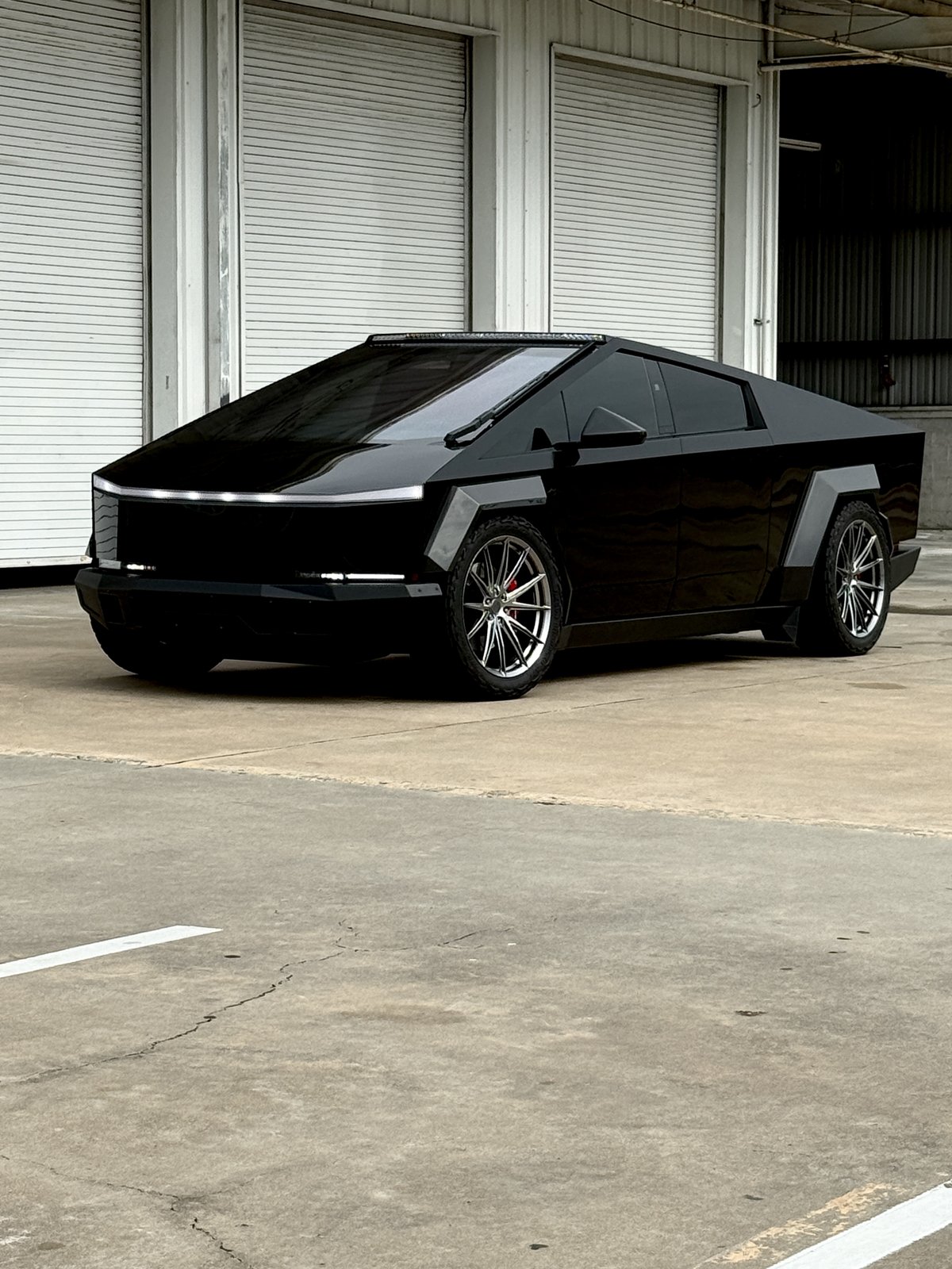 Matte black Cybertruck with silver wheels, red calipers and light bar